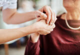 Getty Images-carer-and-older-patient-holding-hands-in-caring-way